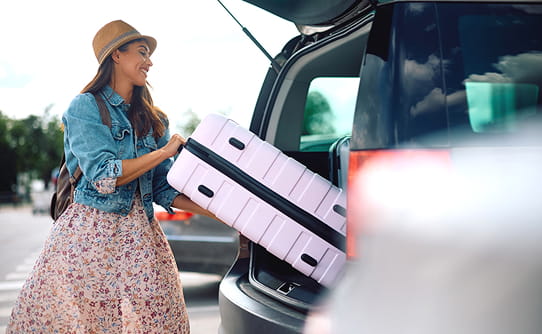 Woman loading car with suitcase